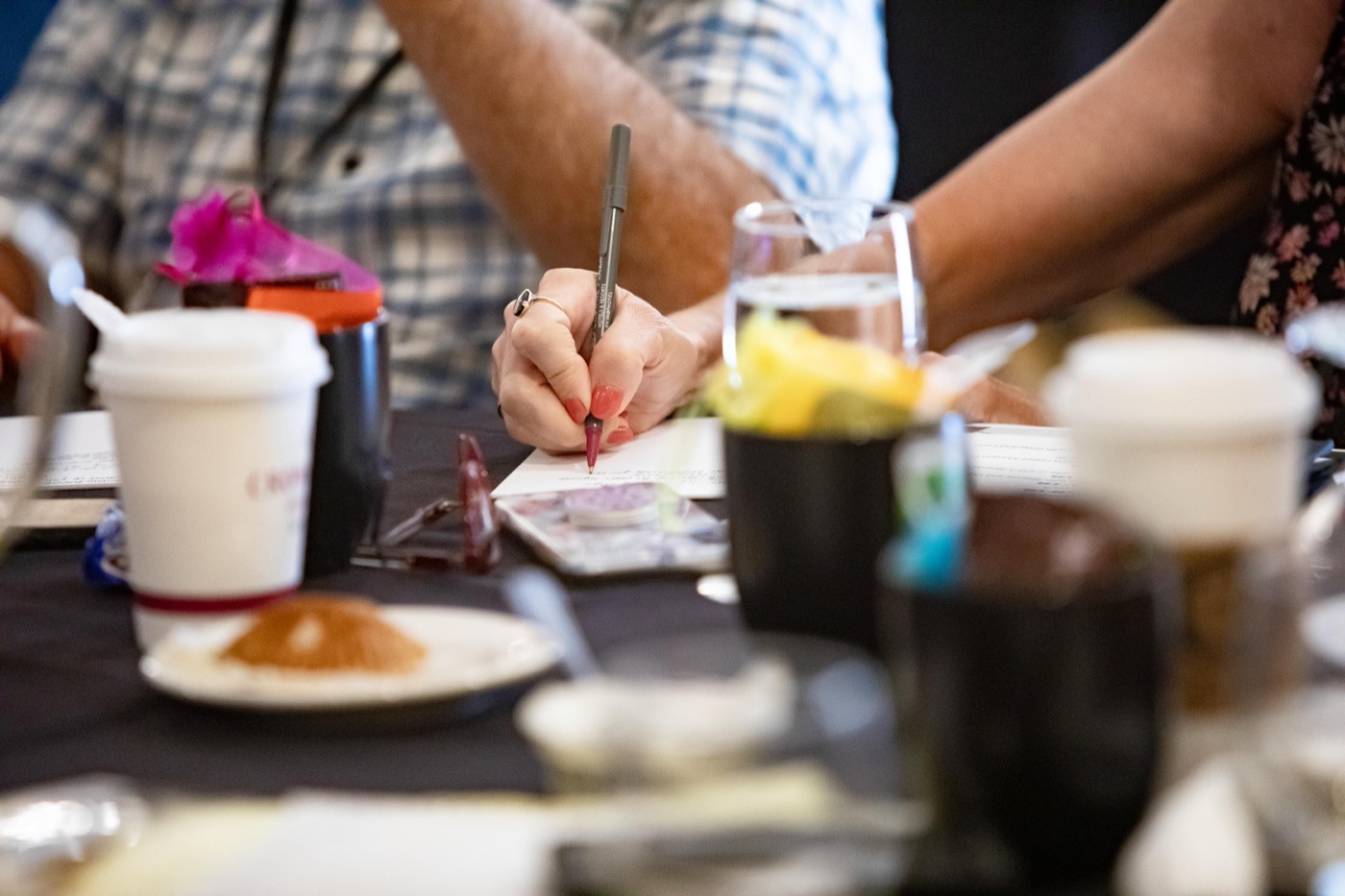 A parent taking notes beside a cup of coffee